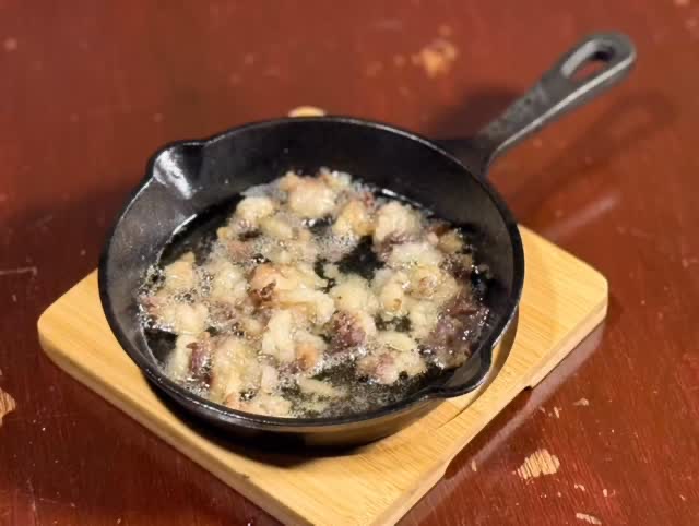 木の台に載せた小さなスキレットで、脂をまとった肉片が焼けている。