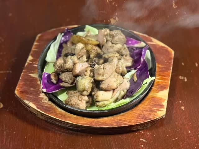 木の台にはめた鉄板に、紫キャベツを敷いて焼いた鶏肉。湯気が上がる。